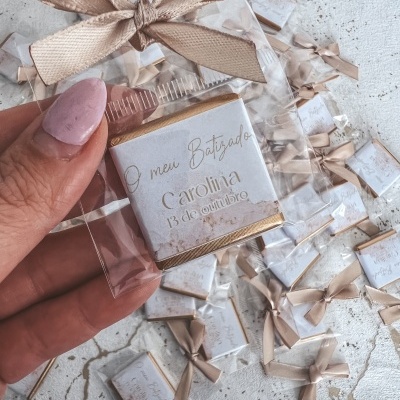 chocolates embrulhados em papel branco com fita bege, texto dourado O meu Batizado Carolina 13 de outubro