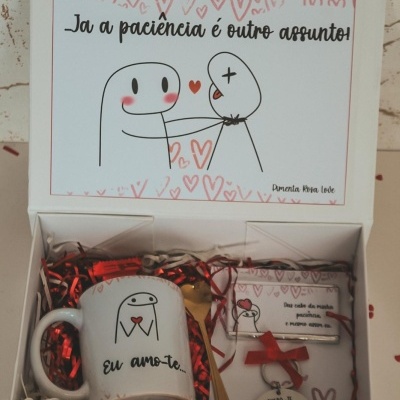 Conjunto de oferta com caneca, colher, chaveiro e cartão com texto e desenho em caixa branca com fita vermelha.