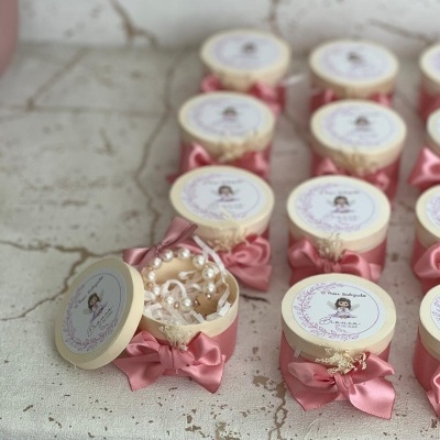 Caixas redondas creme com laços cor de rosa e pulseiras de pérolas, para lembrança de batizado