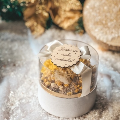 Caixa de presente redonda com flores secas e etiqueta de madeira com texto