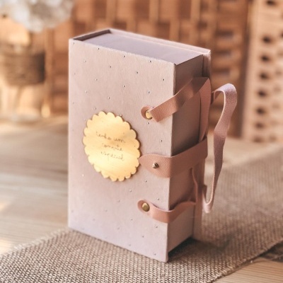 Caixa rosa decorada com alças de fita e placa dourada com texto