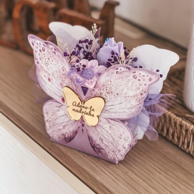 Arranjo decorativo lilás com flores artificiais e ornamento dourado com texto