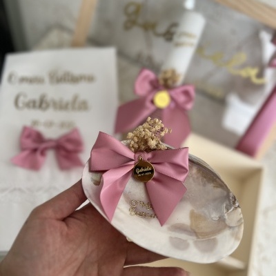 Conjunto de cerimónia com prato de resina, vela decorada, convite e caixa com laços rosa e flores secas