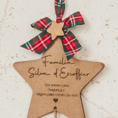 Estrela decorativa de madeira com laço xadrez e texto gravado pendurada