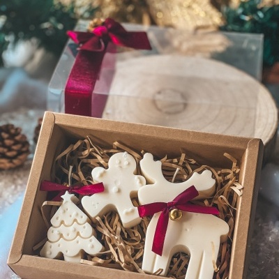 Caixa de velas decorativas em forma de Natal dentro de caixa de cartão com palha decorativa.