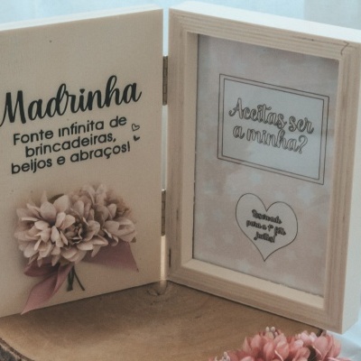 Duas molduras de madeira clara com textos em português e flores cor-de-rosa em suporte de madeira