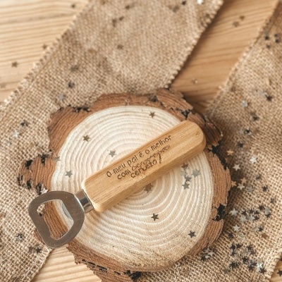 Abridor de garrafas com cabo de madeira gravado sobre base de madeira e tecido rústico com confetes em estrelas