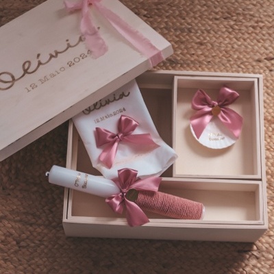 Caixa de madeira com itens decorativos cor de rosa sobre tapete de fibra natural.