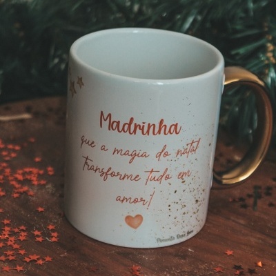 Caneca branca com pega dourada decorada com texto e pequenos corações, decorada para natal
