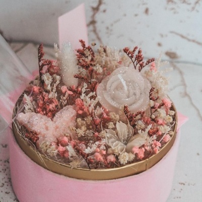 Arranjo floral seco em caixa rosa redonda com tampa dourada