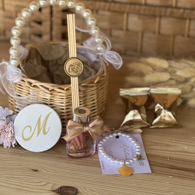 Conjunto presente com cesta de vime, fragrância, pulseira, chocolates e cartão com a letra M dourada