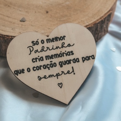 Coração de madeira com texto gravado sobre superfície azul clara e disco de madeira