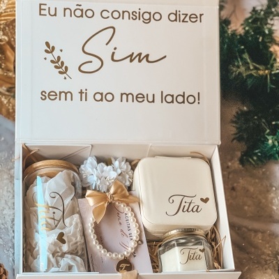 Caixa de presente branca com conteúdo e frase em português na tampa