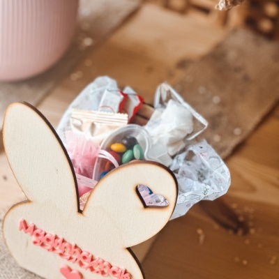 Cesta de madeira em forma de coelho com doces e papéis decorativos