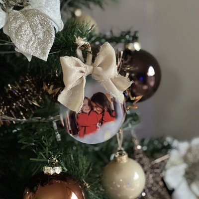 Decoração de Natal com bolas douradas, castanhas e personalizada com laço creme e foto de crianças.