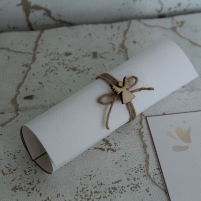 Convite de batizado enrolado em papel branco com cordão rústico e coração de madeira em superfície marmorizada