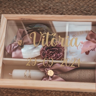 Caixa de presente decorativa com itens rosa e bege e texto dourado na tampa