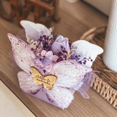 Arranjo de flores artificiais lilás com borboleta dourada com texto