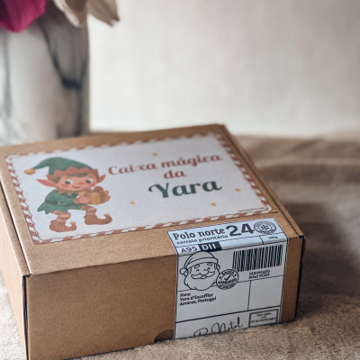 Caixa de cartão castanha com etiqueta ilustrada e selo postal sobre superfície bege