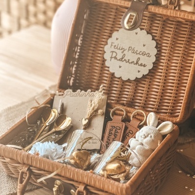 Cesta de vime com copos, colheres, chaveiros e coelhinho de peluche para Páscoa.