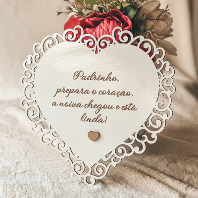 Placa decorativa em forma de coração branca com flores vermelhas e verdes ao fundo