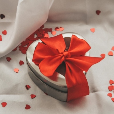 Caixa de presente coração prateada com laço vermelho e confetes em forma de coração