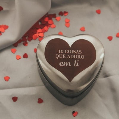 Caixa de coração metálica prateada com texto e corações vermelhos espalhados