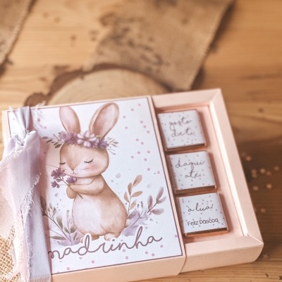 Caixa rosa com coelho decorativo e chocolates com mensagens de Páscoa.