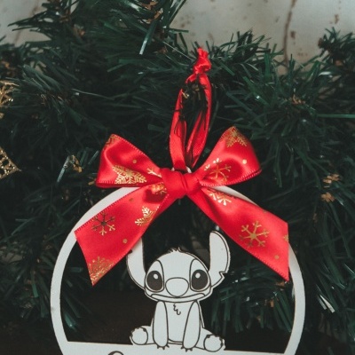 Enfeite de Natal branco com Stitch, laço vermelho e nome Camila pendurado numa árvore de Natal