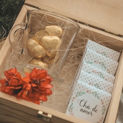 caixa de madeira com chávena de vidro, bombons dourados, saquetas de chá 'Chá de amor' e flores vermelhas artificiais
