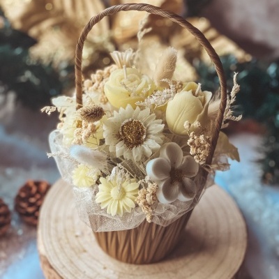 Cesto decorativo com flores artificiais amarelas e bege sobre base de madeira