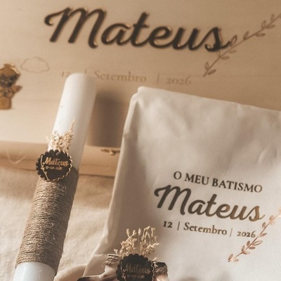 Conjunto de batismo com vela branca, concha decorativa, saco de tecido branco personalizado e caixa de madeira clara.