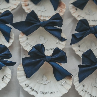 Laços azuis escuros em conchas brancas decorativas para batizado.