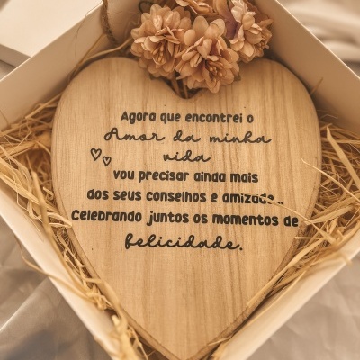 Placa de madeira em forma de coração com texto em português em caixa branca com flores secas