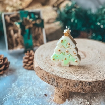 Vela árvore de Natal verde e branca com detalhes dourados sobre madeira