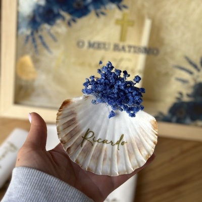 Concha de mar branca com flores azuis secas e nome Ricardo em dourado