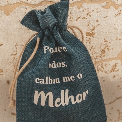 Sacola de tecido azul escuro com texto branco 'Podem todos, calhou me o Melhor' e cordão bege