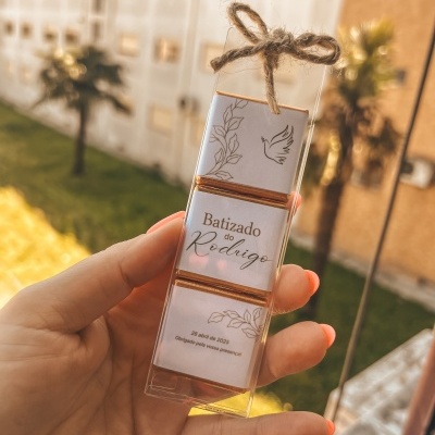Caixa transparente com três chocolates e rótulo branco para batizado com laço de corda