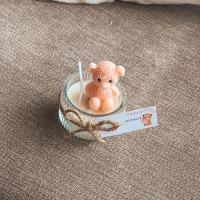 Vela branca em base de vidro com ursinho cor de rosa em cera e etiqueta com cordel castanho