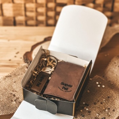 Conjunto de bolsa e porta-chaves em pele castanha com inscrições Super Pal na caixa aberta