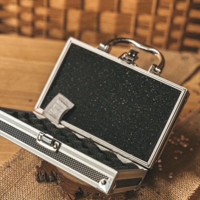 Mala de metal com interior de espuma preta aberta numa superfície de madeira