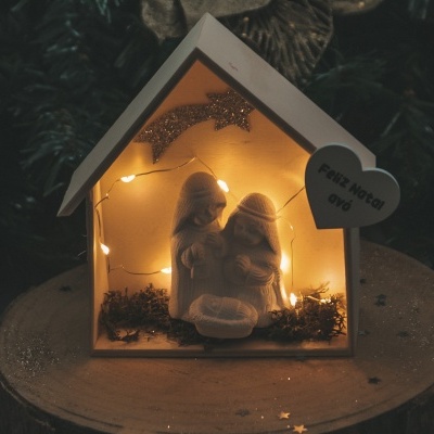 Casa decorativa de madeira com presépio iluminado e coração com texto 'FELIZ NATAL'
