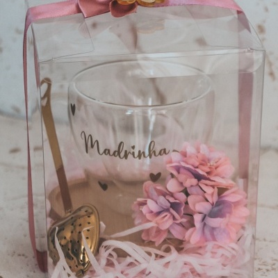 Conjunto de chá com chávena, colher e flores em caixa transparente com fita rosa