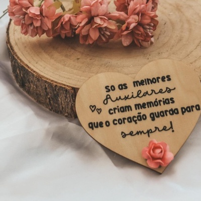 Coração decorativo em madeira clara com texto e flor rosa sobre base de madeira redonda e coroas de flores