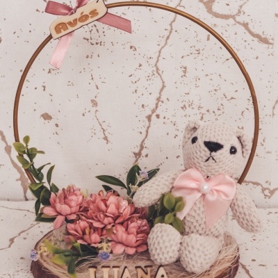 Arranjo decorativo com urso de tricô, flores rosa e placa com nome Luana