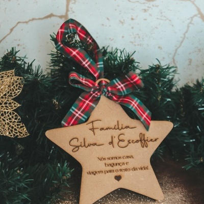 Ornamento de estrela de madeira com laço tartan pendurado numa guirlanda verde