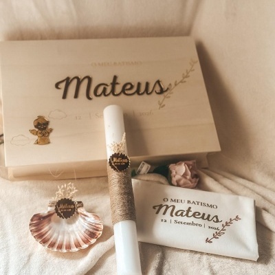 Conjunto de batismo com caixa, vela, concha e t-shirt personalizados com o nome Mateus e data de 12 Setembro 2026 em fundo bege.