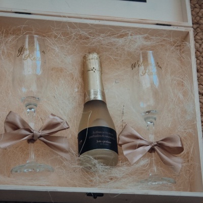 Conjunto de presente com garrafa pequena de champanhe e duas taças com laços numa caixa branca