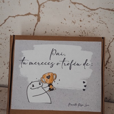 Caixa com etiqueta com ilustração de figura a segurar troféu e texto em português