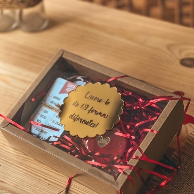 Caixa de presente com embalagem e placa amarela com texto em cima de mesa de madeira